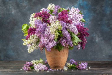 Ahşap masadaki seramik vazoda leylak..