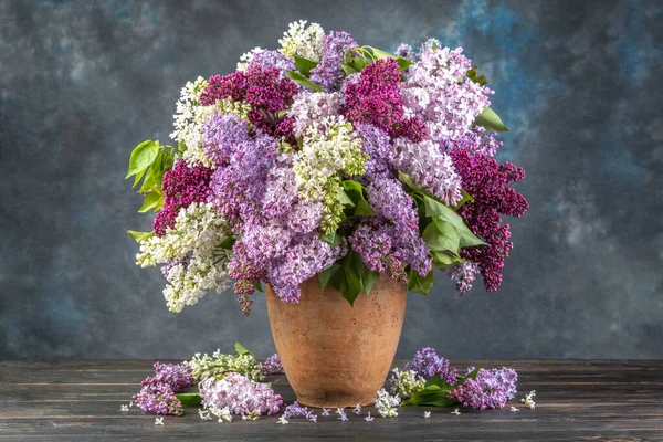 Ahşap masadaki seramik vazoda leylak..