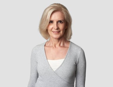 Güzel yaşlı kadın gülümsüyor. Gri duvar arka plan üzerinde izole. 