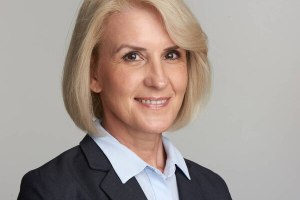 Портрет веселой старшей бизнес-леди, смотрящей в камеру. Улыбающаяся исполнительница средних лет. Студия изолирована
