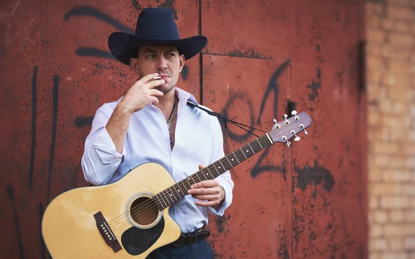 Handsome Man Wearing Cowboy Hat Smoking Cigarette Holding Acoustic Guitar — Stock Photo, Image