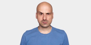 adam onun kaş kaldırdı. Mavi t-shirt kızgın kel adam. Gri arka plan üzerinde izole