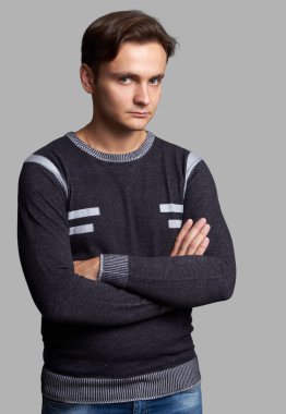 Katlanmış ellerle emin yakışıklı adam. Gri arka plan üzerinde izole