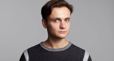 Yakışıklı adam stüdyo gri arka plan üzerinde izole kamera bakıyor