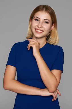 Gri studio arka plan üzerinde izole mavi elbiseli neşeli güzel kadın