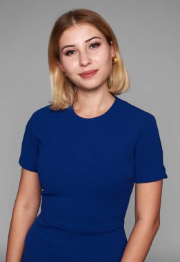 Mavi elbiseli güzel kız smilinh var. gri studio arka plan üzerinde izole