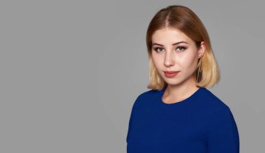 Mavi elbiseli güzel kız smilinh var. gri studio arka plan üzerinde izole