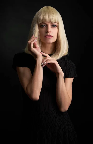 Beautiful model woman in a blonde wig. Care and beauty of hair. Black background