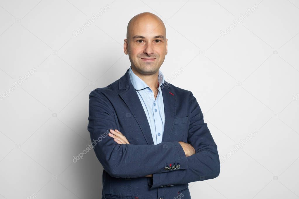Cheerful handsome bald man wearing fashionable casual clothes. Isolated on grey studio background