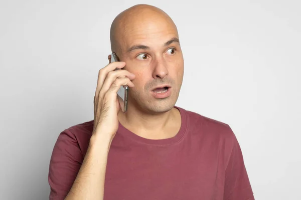 Шокированный лысый мужчина с телефоном — стоковое фото