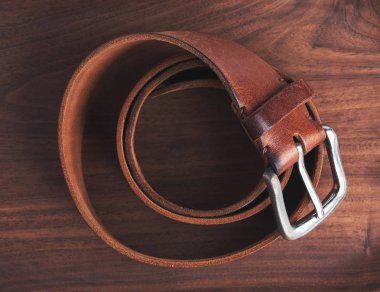 Ahşap arka planda eski kahverengi deri kemer