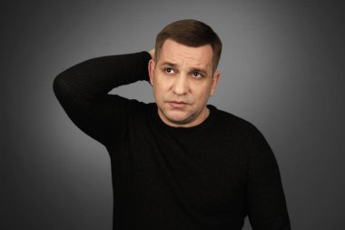 Siyah kazak adam düşünüyor ve yukarı bakıyor