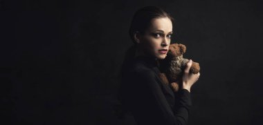 üzgün kadın bir oyuncak ayı oyuncağı tutar