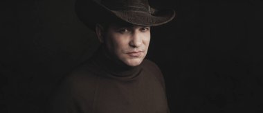 adam siyah stüdyo arka planda kovboy şapka giyiyor