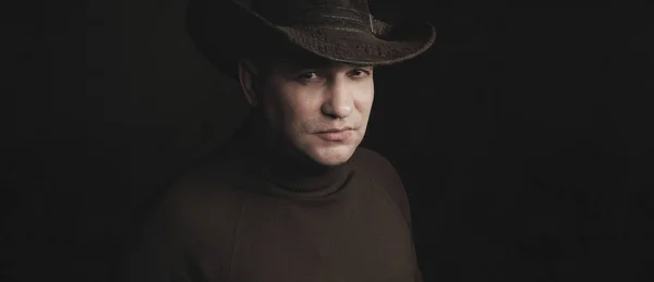 Człowiek ubrany kowboj kapelusz nad czarnym studio tło — Zdjęcie stockowe