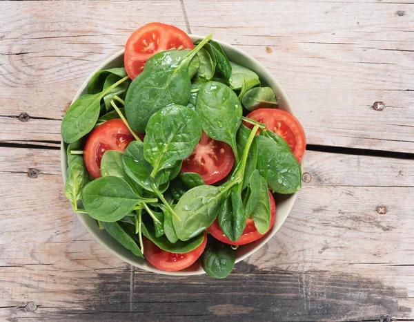 Spenat och tomatsallad på ett träbord. uppifrån och — Stockfoto