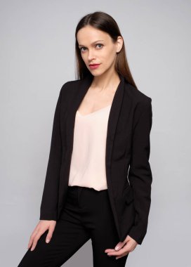 Gri arka planda siyah ceketli bir kadın.