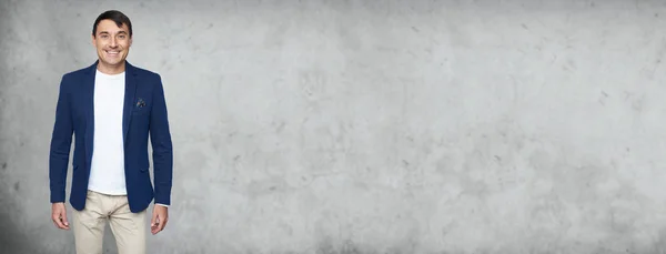 Modieuze man glimlacht staande over grijze Studio muur — Stockfoto