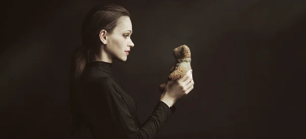 Mooie vrouw houdt een Teddy Bear speelgoed over zwarte achtergrond — Stockfoto