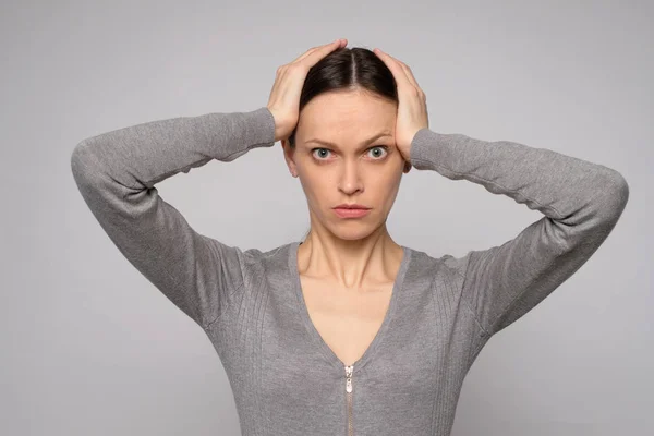 Mujer conmocionada sostiene su cabeza en las manos — Foto de Stock