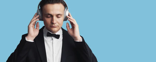 Young man listening to music on blue background — 스톡 사진