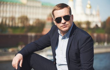 Takım elbiseli ve güneş gözlüklü kendine güvenen bir iş adamı. Dış mekan portresi