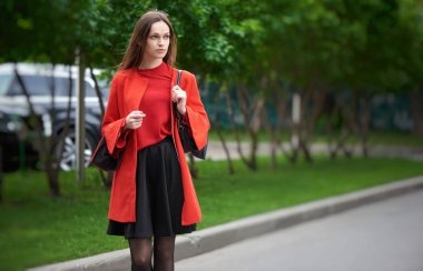 Güzel esmer genç kadın kırmızı ceket giyiyor ve yürüyüş