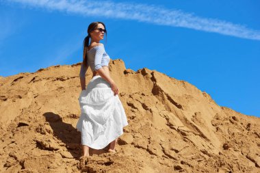 Modaya uygun kadın çölde bir kumun üzerinde duruyor.