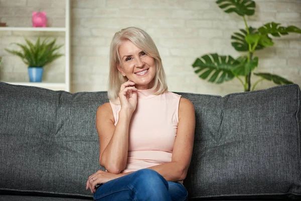 Die schöne 50-jährige Frau sitzt zu Hause auf einem Sofa. Glücklicher Junge — Stockfoto