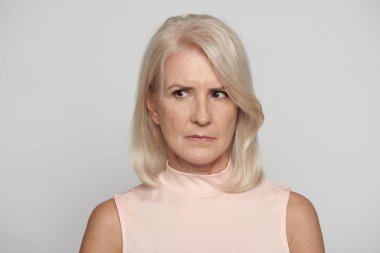 Kızgın güzel yaşlı bayan gri izole uzak bakıyor