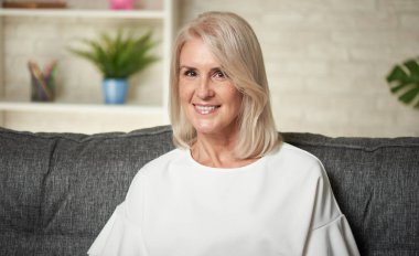 Güzel yaşlı bayan evde bir kanepede oturuyor