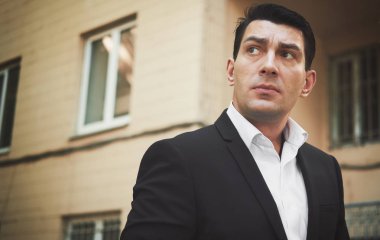 Siyah takım elbiseli bir adamın açık hava portresi yukarı bakıyor