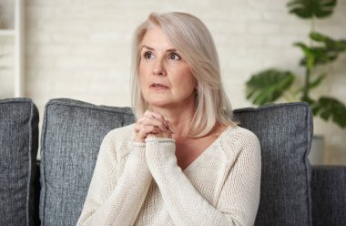 Güzel 50 yaşında sarışın kadın evde kanepede oturan