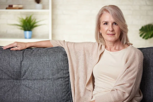 Bella donna di 50 anni che si rilassa sul divano a casa — Foto Stock