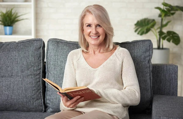 Bella donna di 50 anni che legge un libro di testo inglese — Foto Stock
