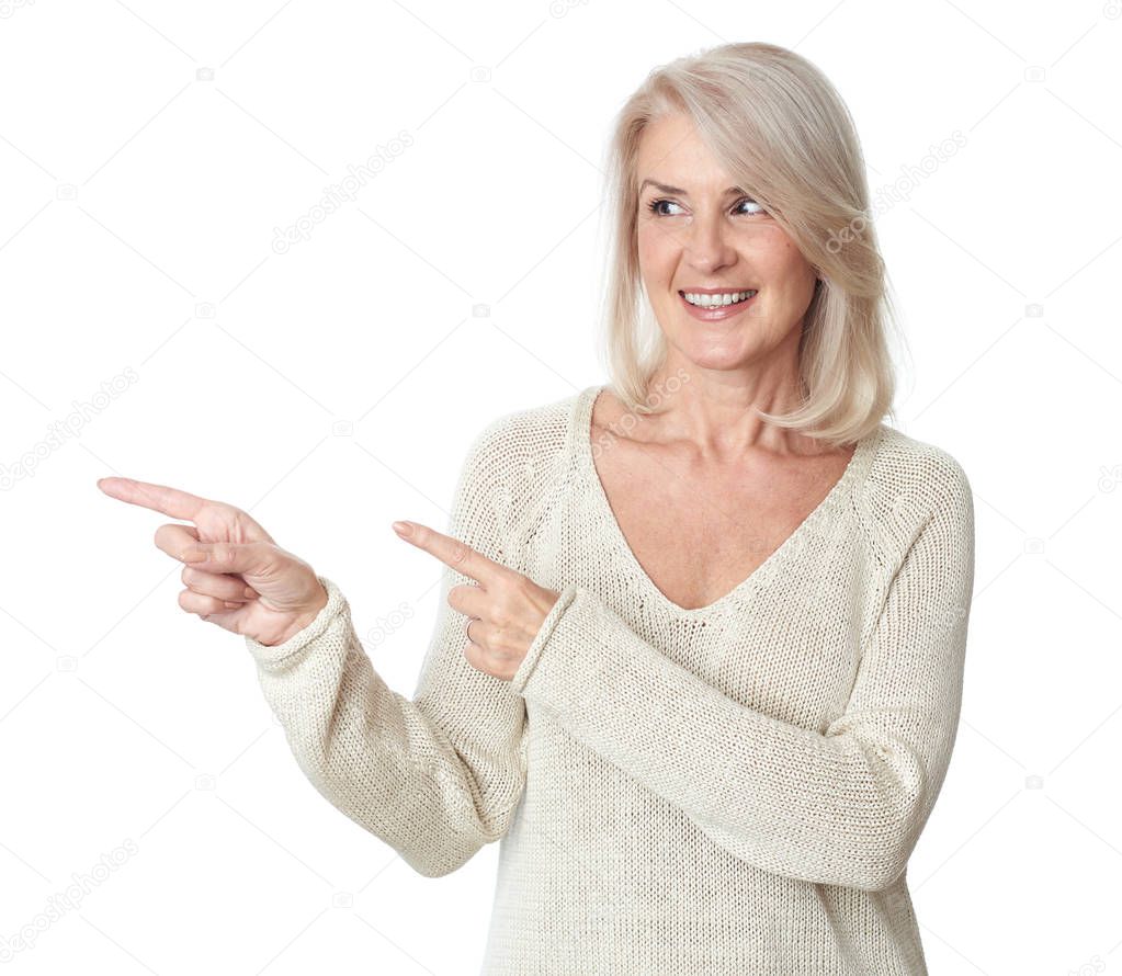 Cheerful 50 years old woman is pointing fingers to copy space