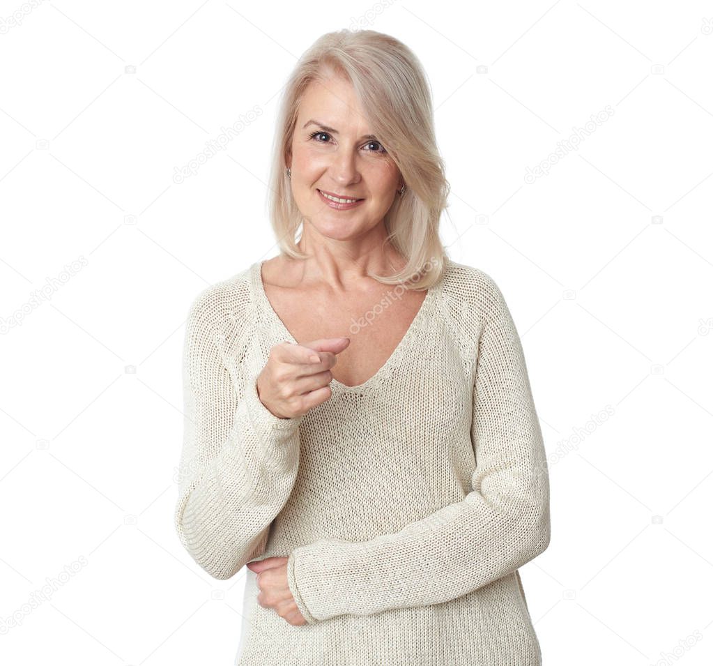 Beautiful 50 years old blonde woman is pointing finger at you. Isolated on white