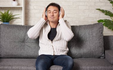 Mutlu adam evde müzik dinliyor.