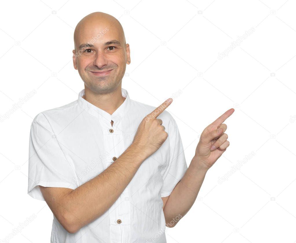 Happy handsome bald man in casual shirt pointing away. Isolated