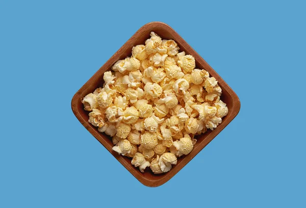 Popcorn in een kom geïsoleerd op blauwe achtergrond. Bovenaanzicht — Stockfoto