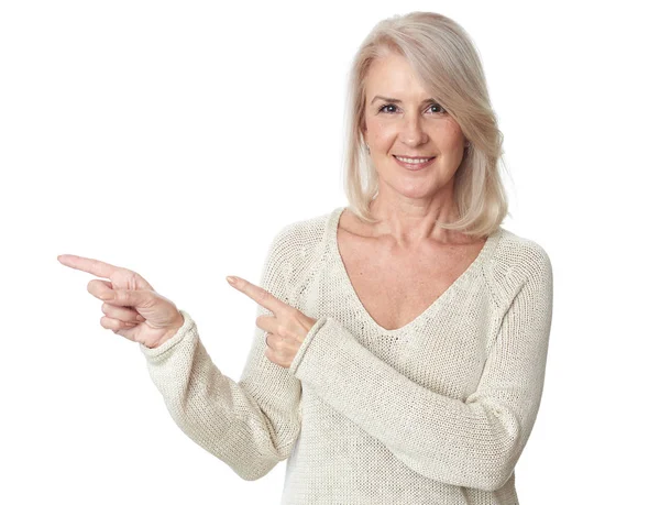 Elegante 50 jaar oude vrouw wijzend naar witte achtergrond — Stockfoto