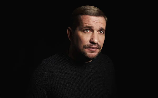 Man in the dark. Portrait of a bearded guy in black sweater — Stock Photo, Image