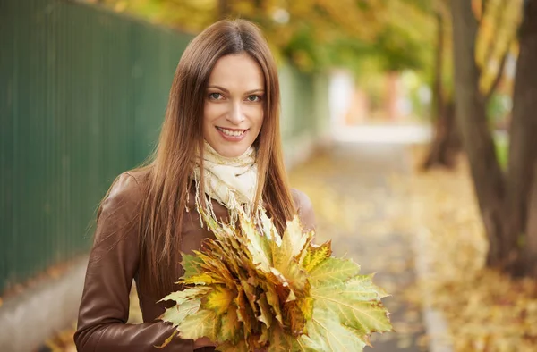 Carino donna sorridente che tiene foglie autunnali nella natura — Foto Stock