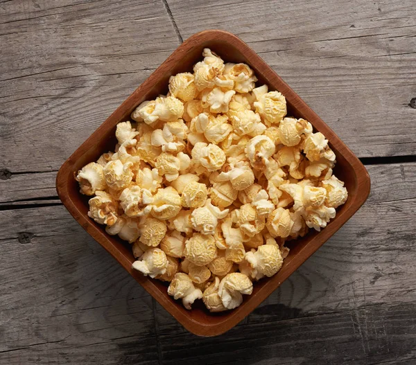 Popcorn in een kom op houten tafel. Bovenaanzicht — Stockfoto