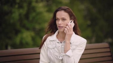 Yaz parkında güzel bir kadın cep telefonuyla konuşuyor. Akıllı telefon kullanan mutlu kız.
