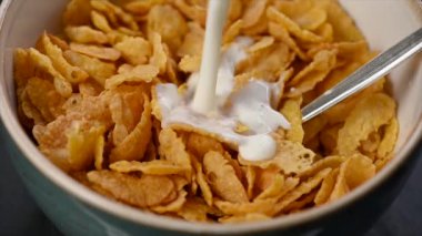 Bir kase mısır gevreğine süt dökerek.