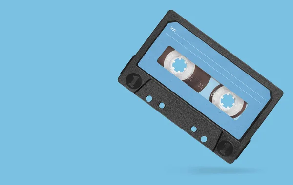 Old audio tape compact cassette with blank label isolated on blue background. Clipping path