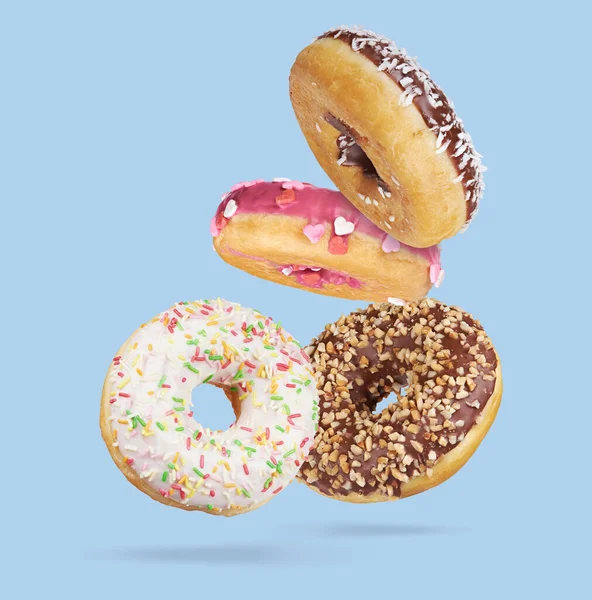 Meng Van Veelkleurige Zoete Donuts Met Hagelslag Blauwe Achtergrond Vliegende — Stockfoto