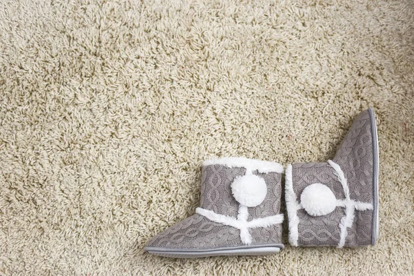 Indoor gray fur slippers on light carpet