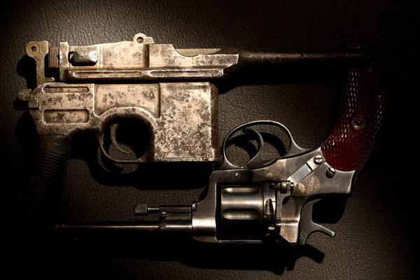 Старый револьвер и пистолет крупным планом на темном фоне